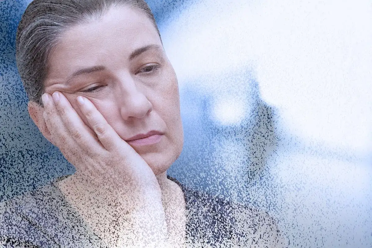 Zmęczona kobieta z dłonią na policzku, symbolizująca mgłę covidową i długotrwałe skutki choroby.