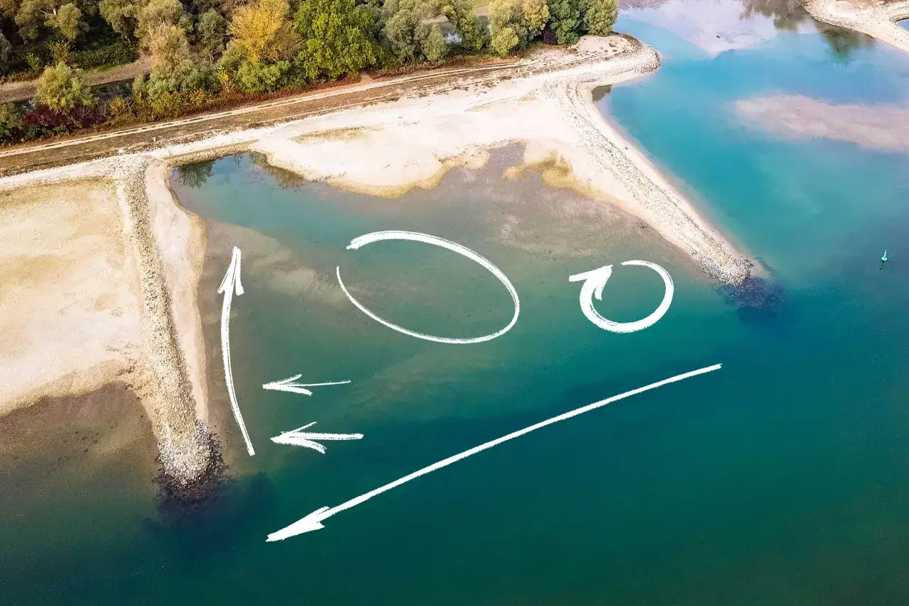 Luftaufnahme einer Sandbank in der Elbe mit weißen Pfeilen und Kreisen, die Strömungen oder Angelplätze markieren.