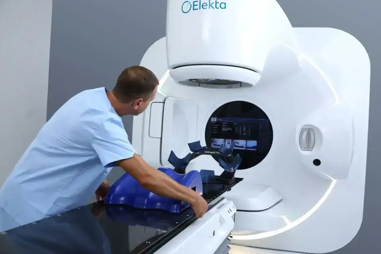Medyk przygotowuje pacjenta do radioterapii na nowoczesnym urządzeniu Elekta.