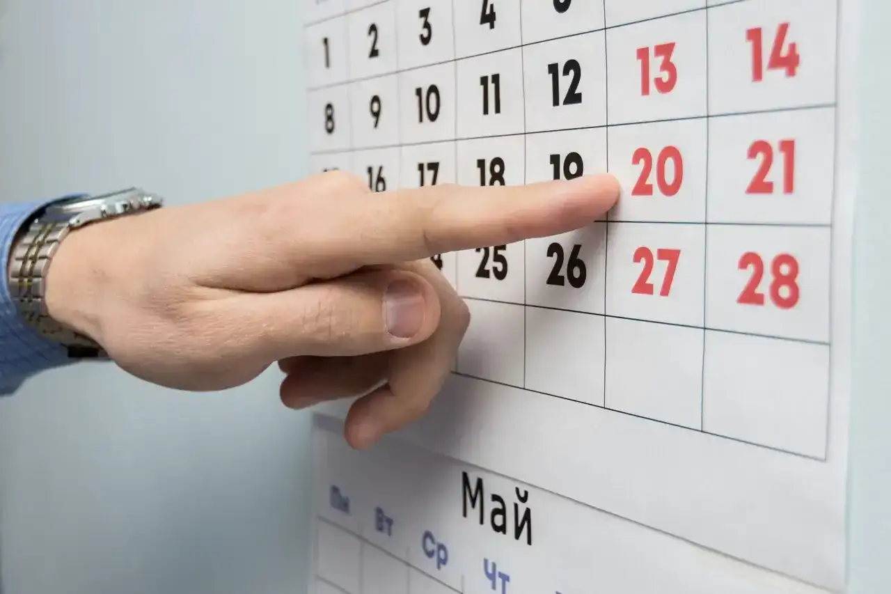 Palec wskazuje datę 20 na kalendarzu, symbolizującą okres wypowiedzenia umowy o pracę na czas nieokreślony.