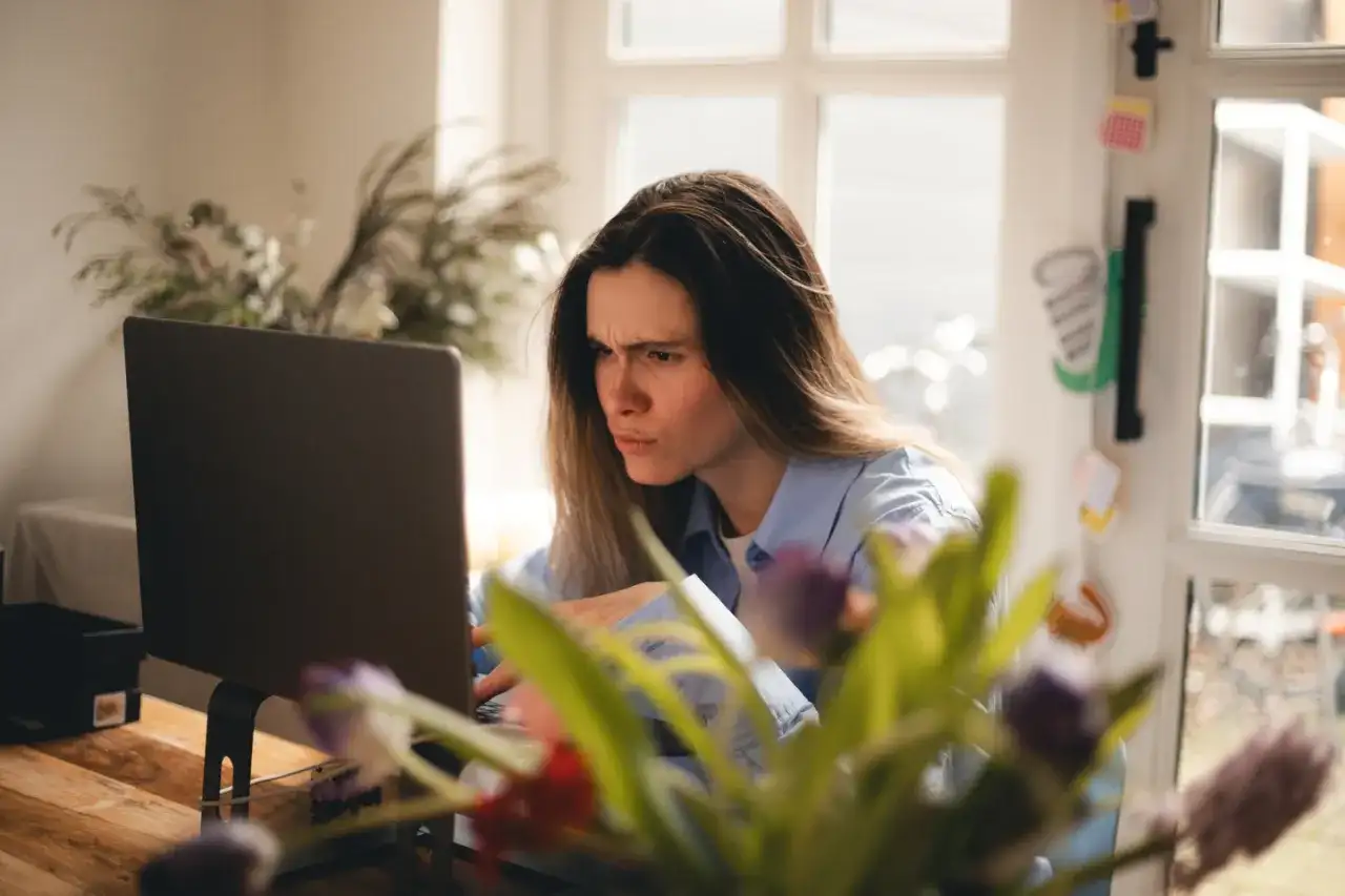 Zmarszczona kobieta przy laptopie, sfrustrowana z powodu braku połączenia z internetem.