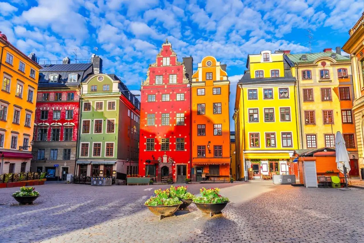 Kolorowe kamienice na placu w Gamla Stan, Sztokholm, pod błękitnym niebem z chmurami.