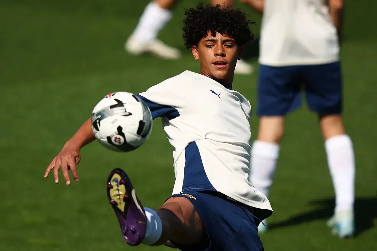 Młody piłkarz, niczym cr7 jr., trenuje na boisku, wykonując efektowne kopnięcie.