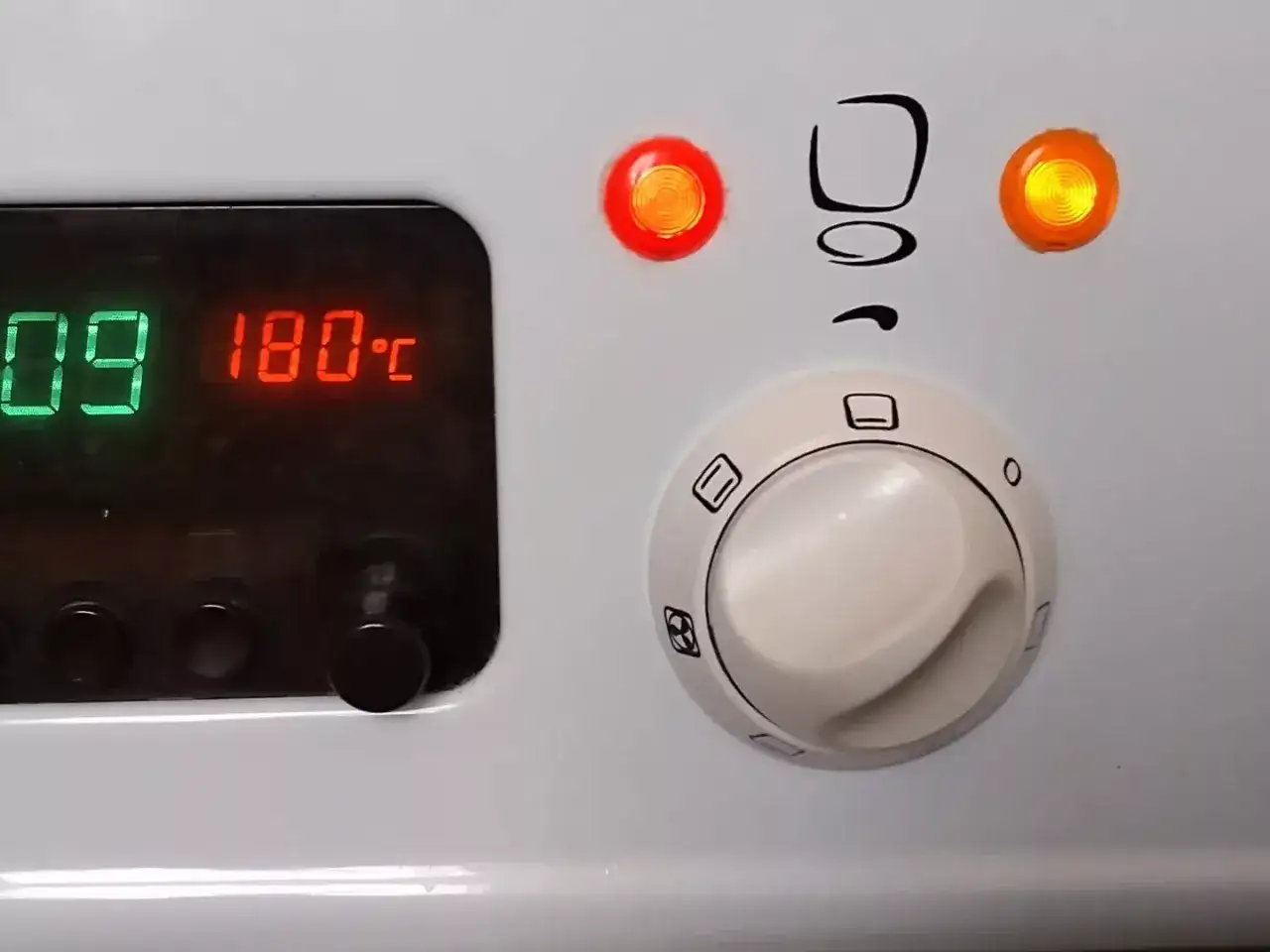 Cyfrowy wyświetlacz piekarnika Mastercook pokazuje 180°C. Pokrętła sterujące i kontrolki są widoczne.