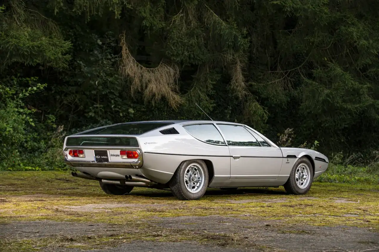 Srebrny Lamborghini Espada z lat 70. na tle zieleni. Klasyk motoryzacji.