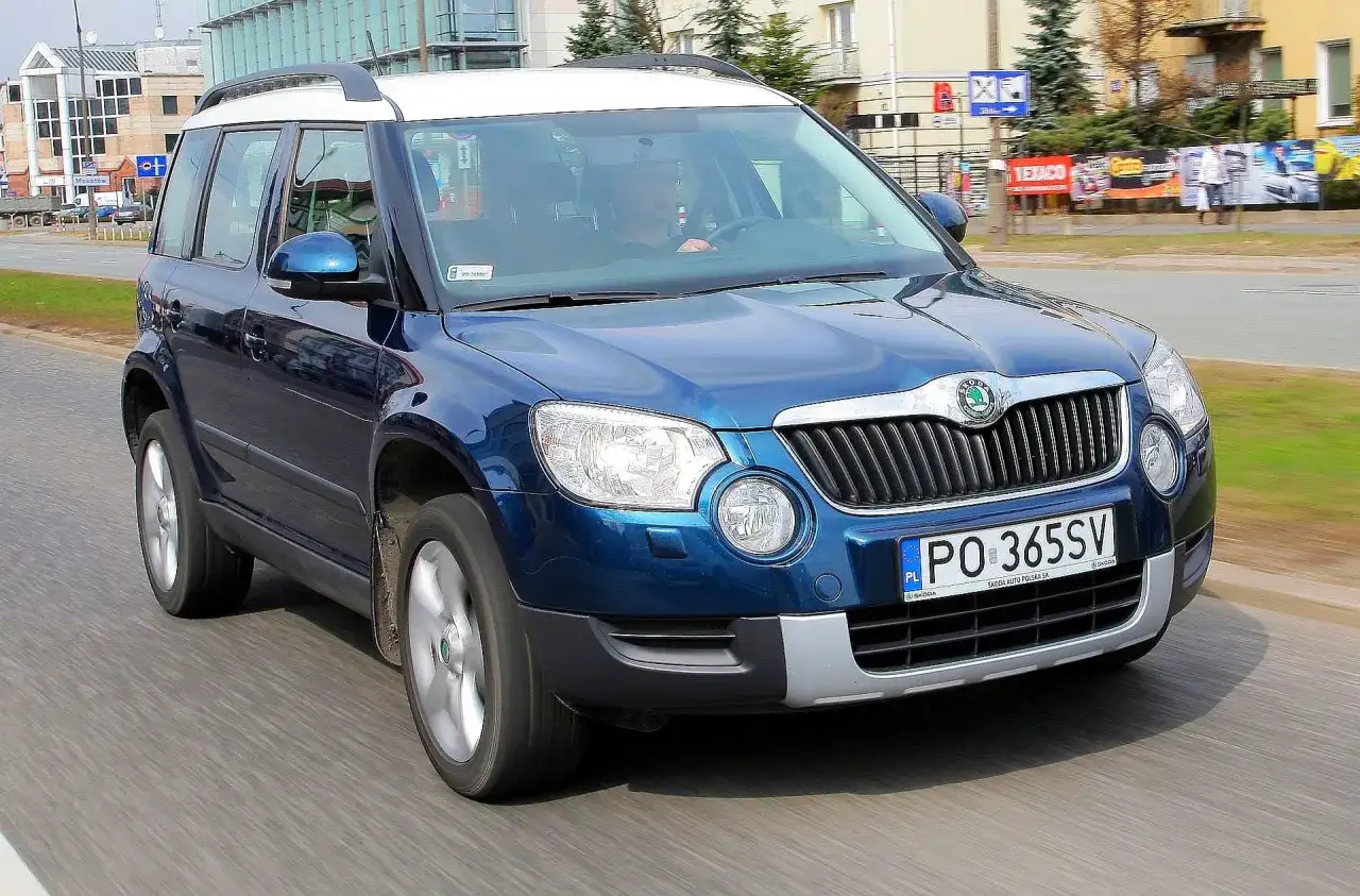 Niebieska Skoda Yeti na drodze. Kierowca w środku. Wiele pozytywnych skoda yeti opinie o tym modelu.
