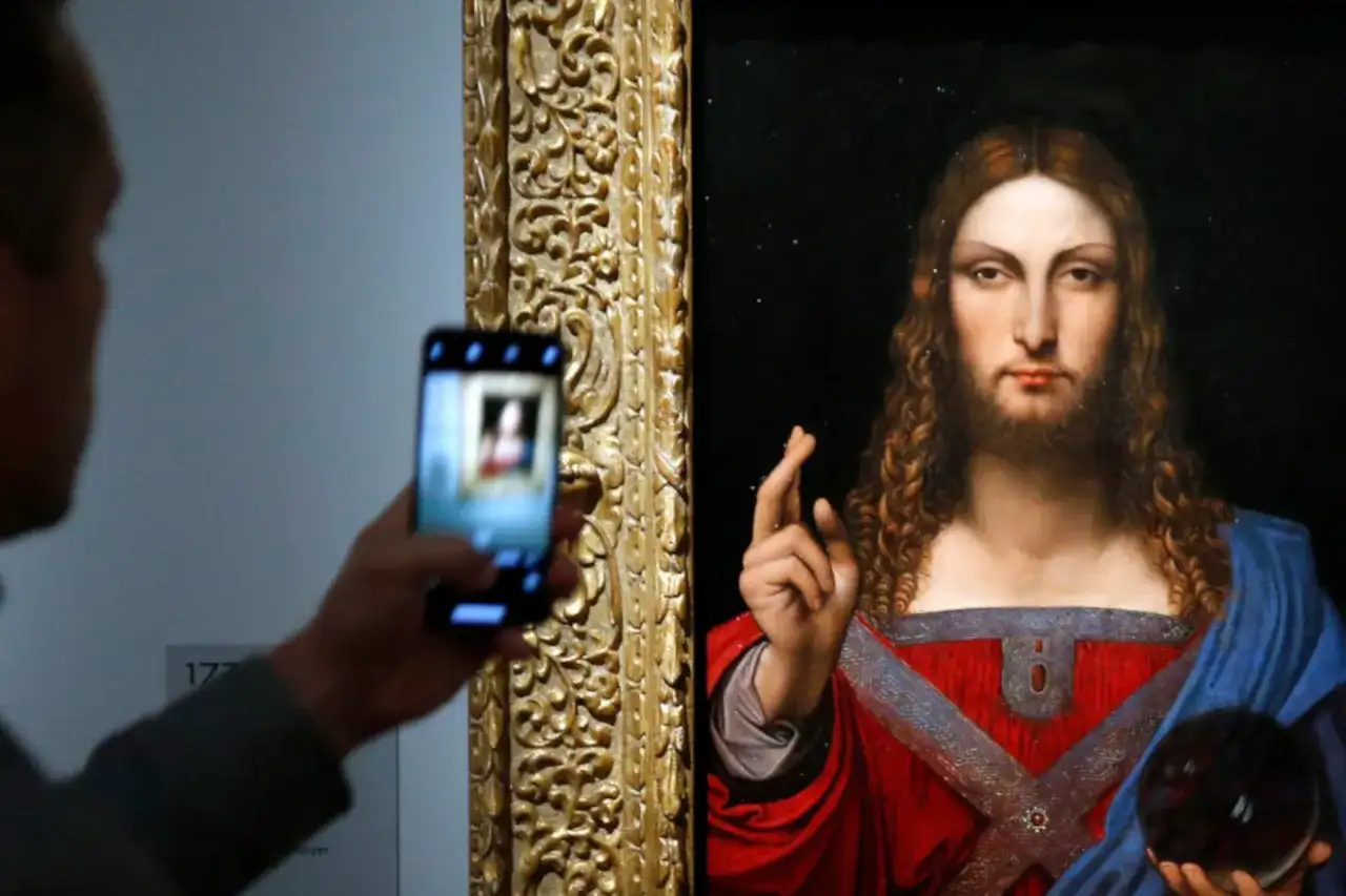 Osoba robi zdjęcie telefonem komórkowym obrazu "Salvator Mundi" przedstawiającego Jezusa.