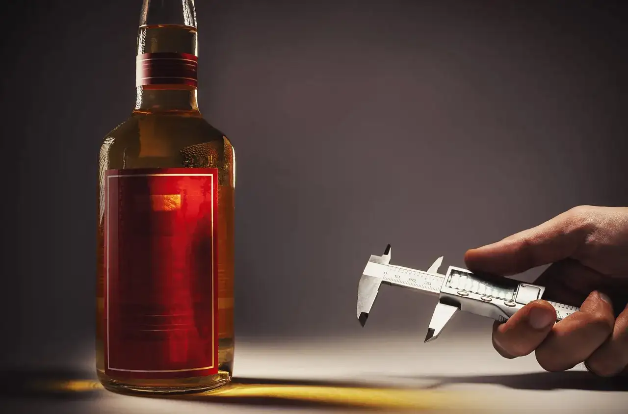 Dłonią trzymam suwmiarkę, mierząc ile procent ma whisky w butelce.