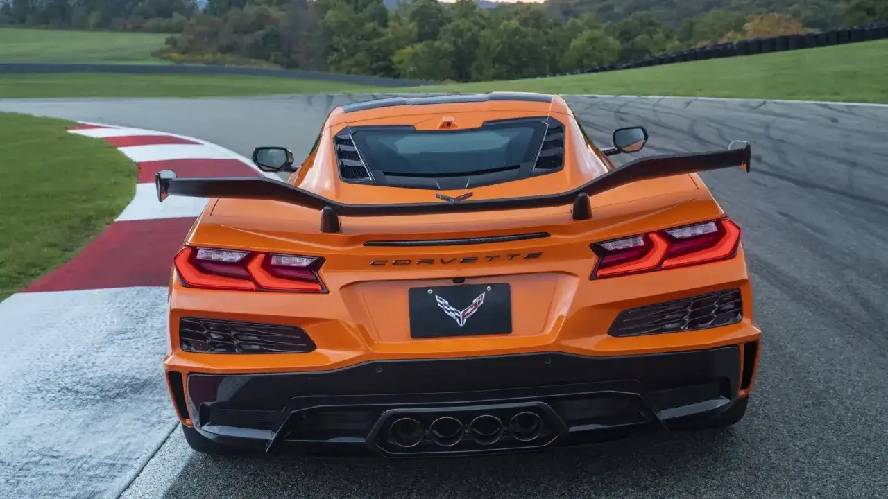 Pomarańczowy Corvette C9 z dużym spojlerem na torze wyścigowym.