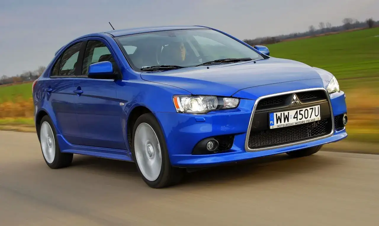 Niebieski Mitsubishi Lancer 9 w ruchu, z widocznym kierowcą i polskimi tablicami rejestracyjnymi.