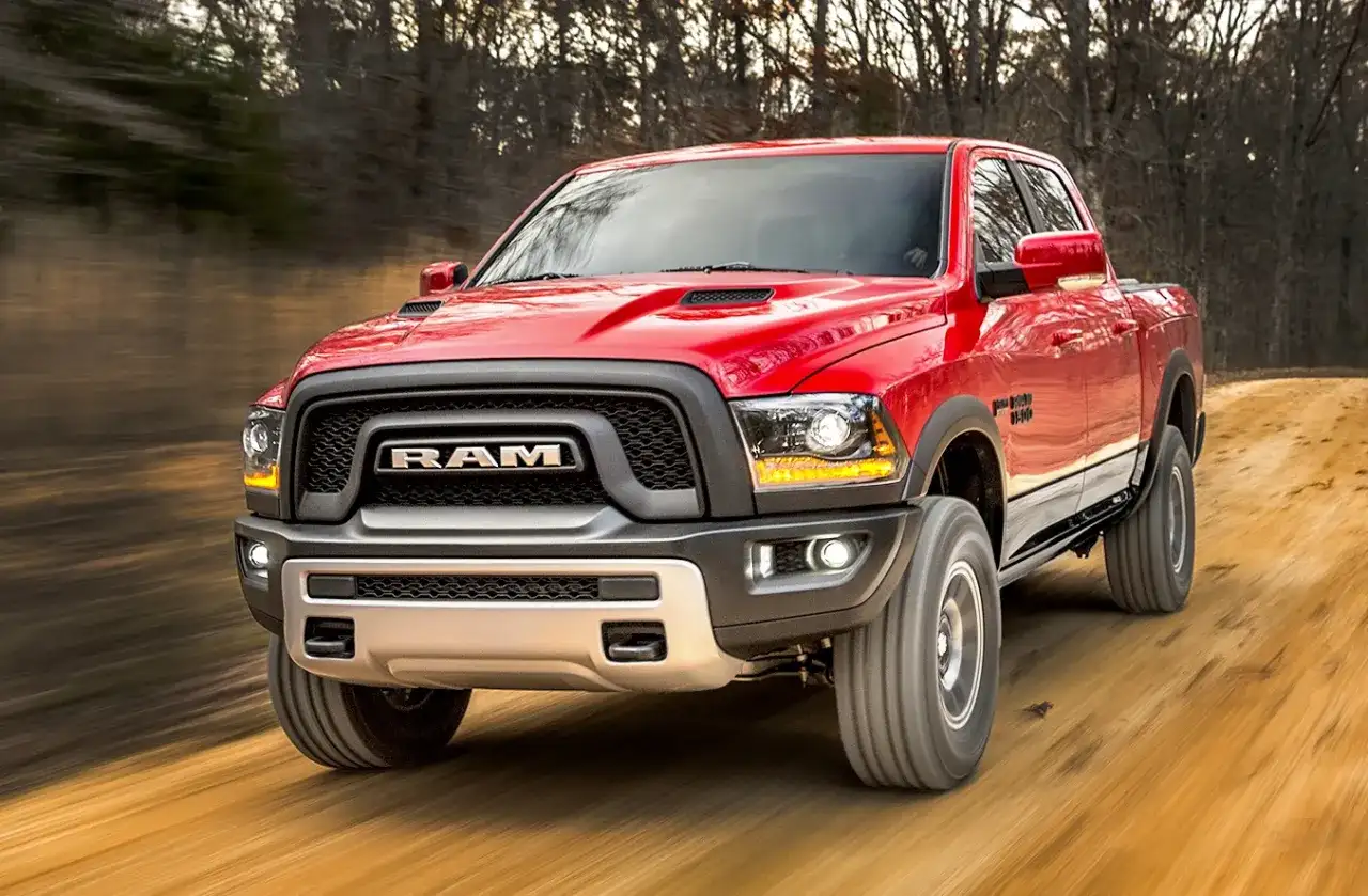 Czerwony Dodge Ram Rebel pędzi po leśnej drodze. Poznaj jego imponujące dodge ram wymiary i możliwości terenowe.