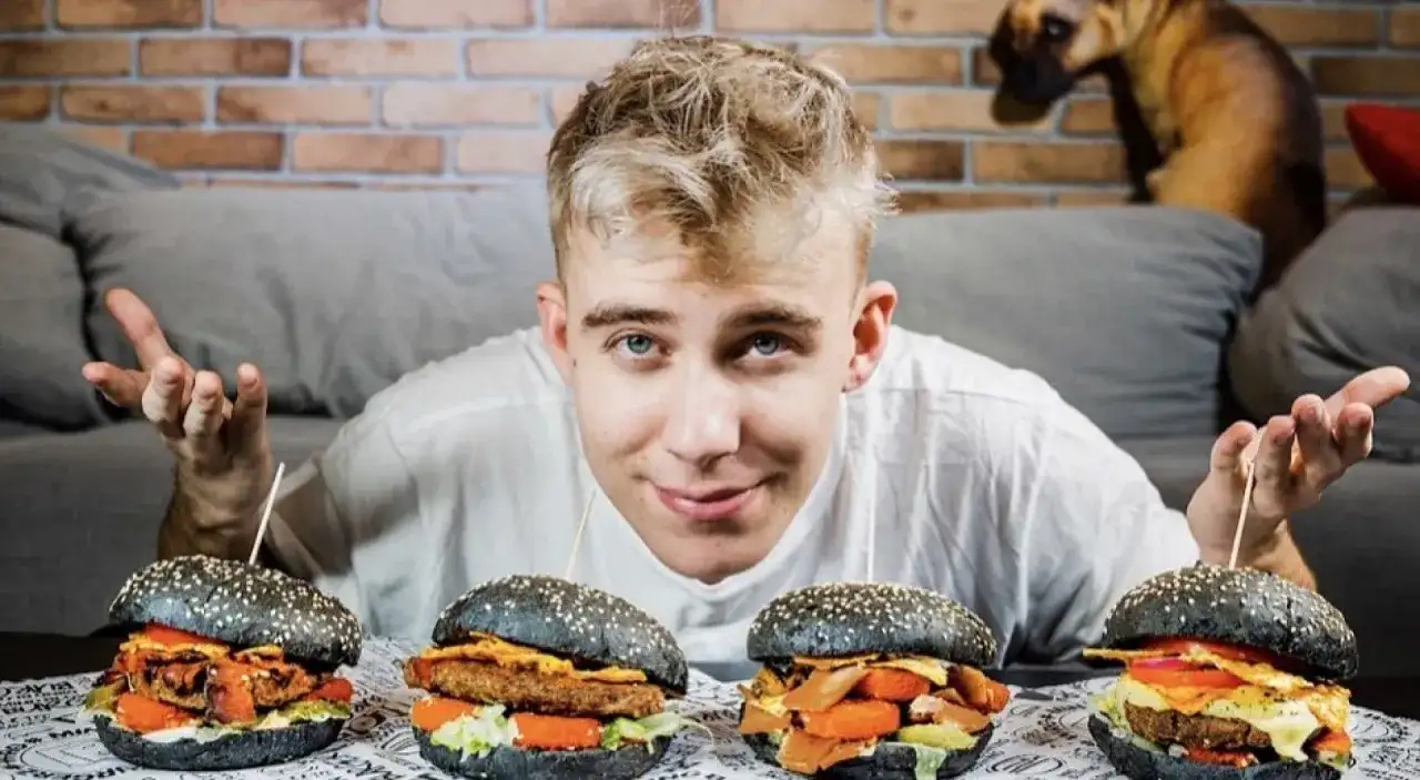 Młody mężczyzna prezentuje cztery burgery w ramach porównania burgerów od znanych youtuberów. Który jest najlepszy?