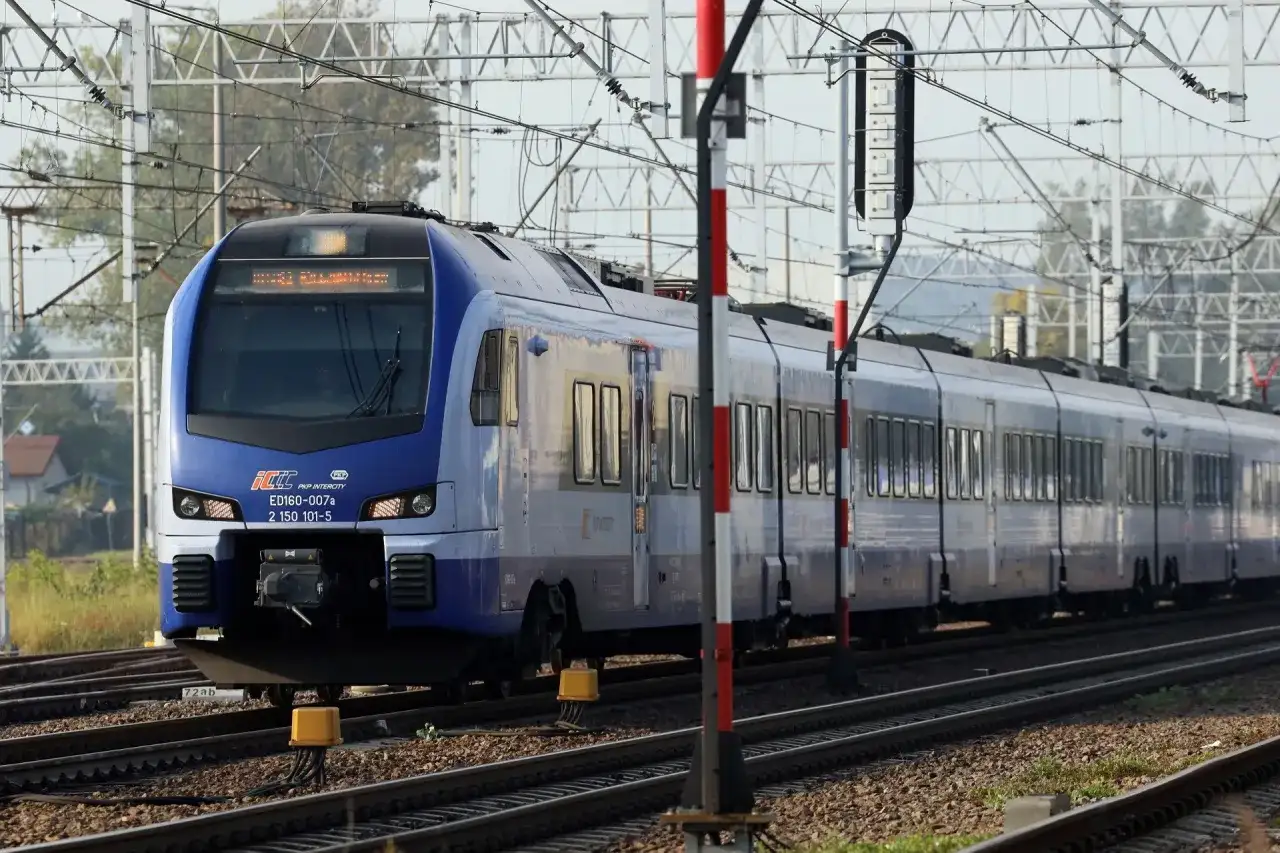 Niebieski pociąg PKP Intercity ED160-007a, kursujący na trasie Zamość - Kraków, zbliża się do stacji.