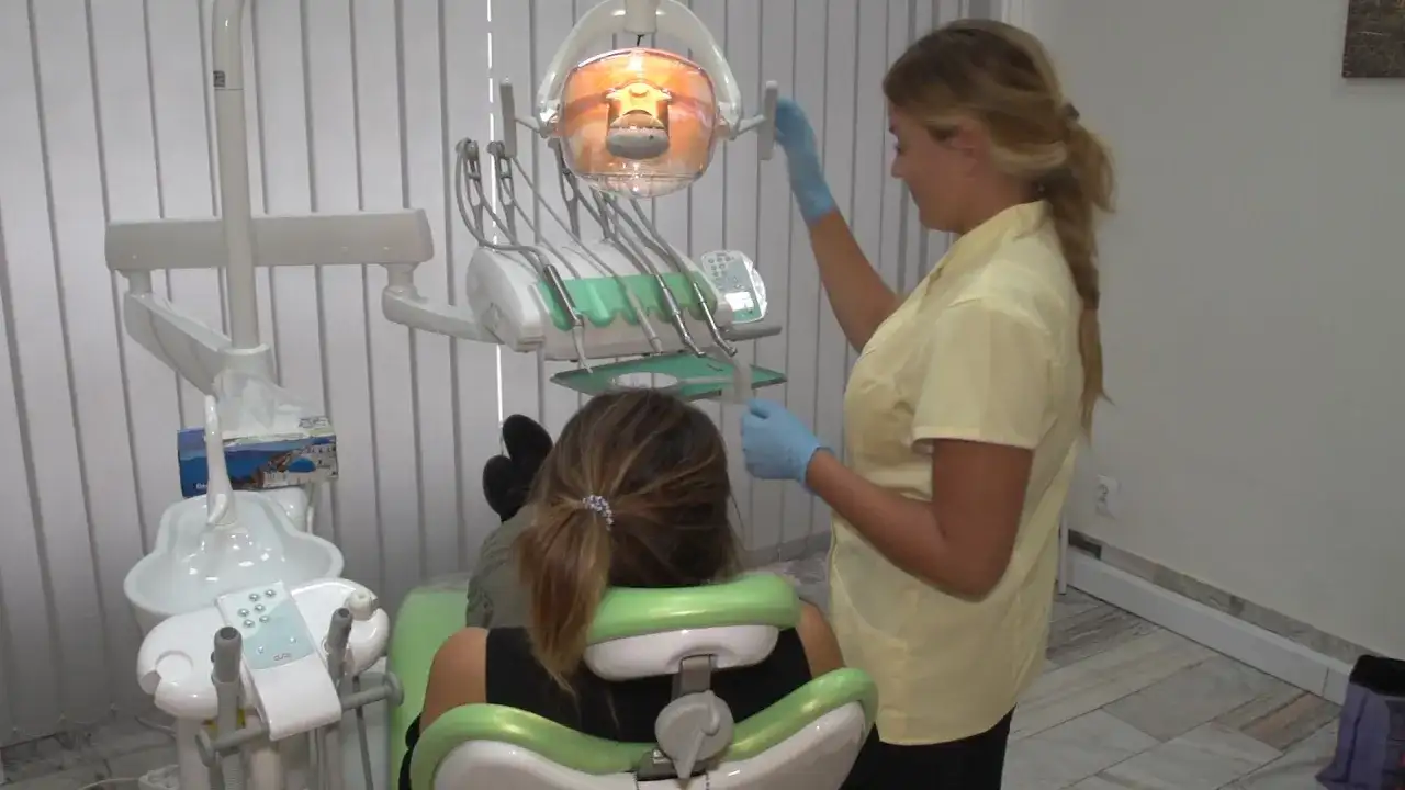 Dentystka przygotowuje znieczulenie w sprayu dla pacjentki siedzącej na fotelu.