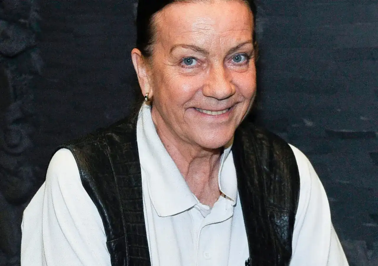 Barbara Burska uśmiecha się, nosząc czarną kamizelkę na białej koszuli.