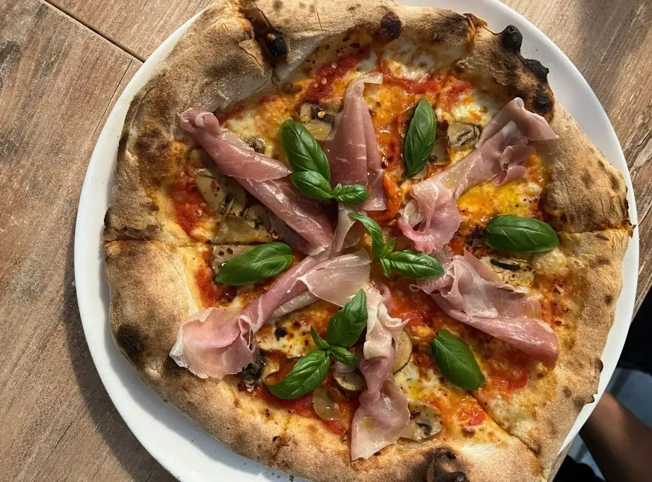 Pyszna pizza z szynką parmeńską i bazylią. Warto sprawdzić ceny w Chorwacji, bo takie smakołyki są warte swojej ceny!