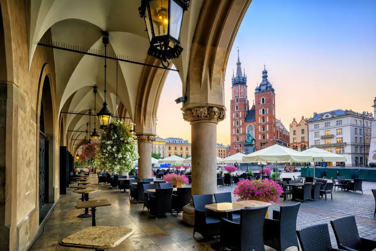Krakowskie Sukiennice, co to? To historyczne miejsce z kawiarnianymi stolikami i widokiem na Kościół Mariacki.