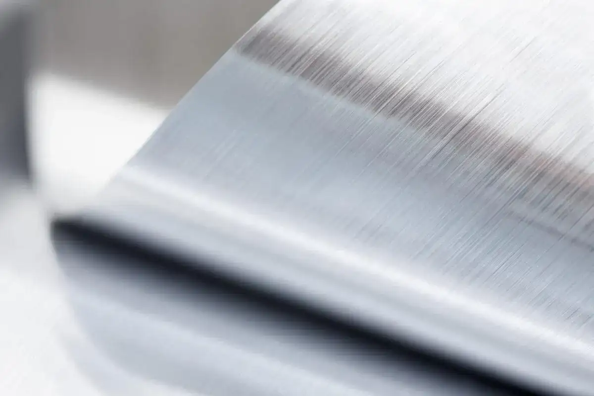 Szczotkowana powierzchnia metalu po procesie anodowania, z widocznymi równoległymi liniami.