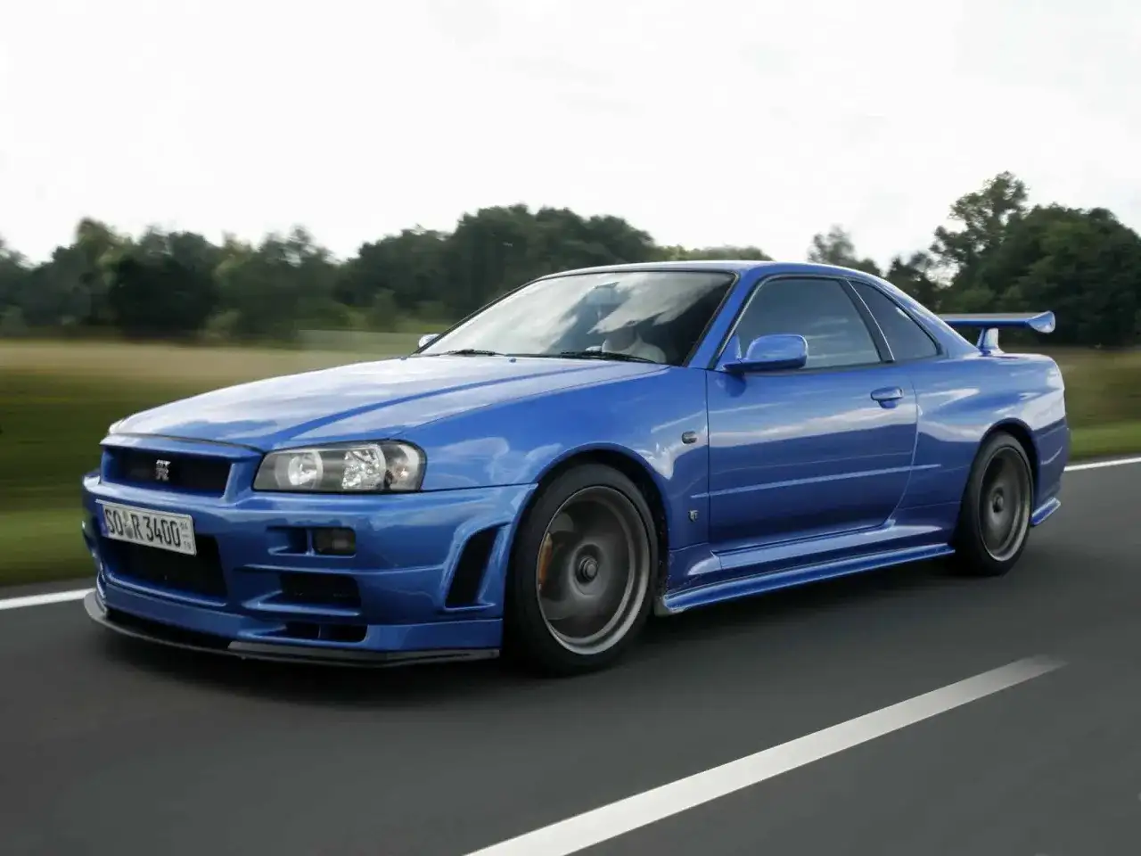 Niebieski Nissan Skyline GT-R R34 w ruchu. Marzenie wielu fanów motoryzacji, a jego cena wciąż rośnie.