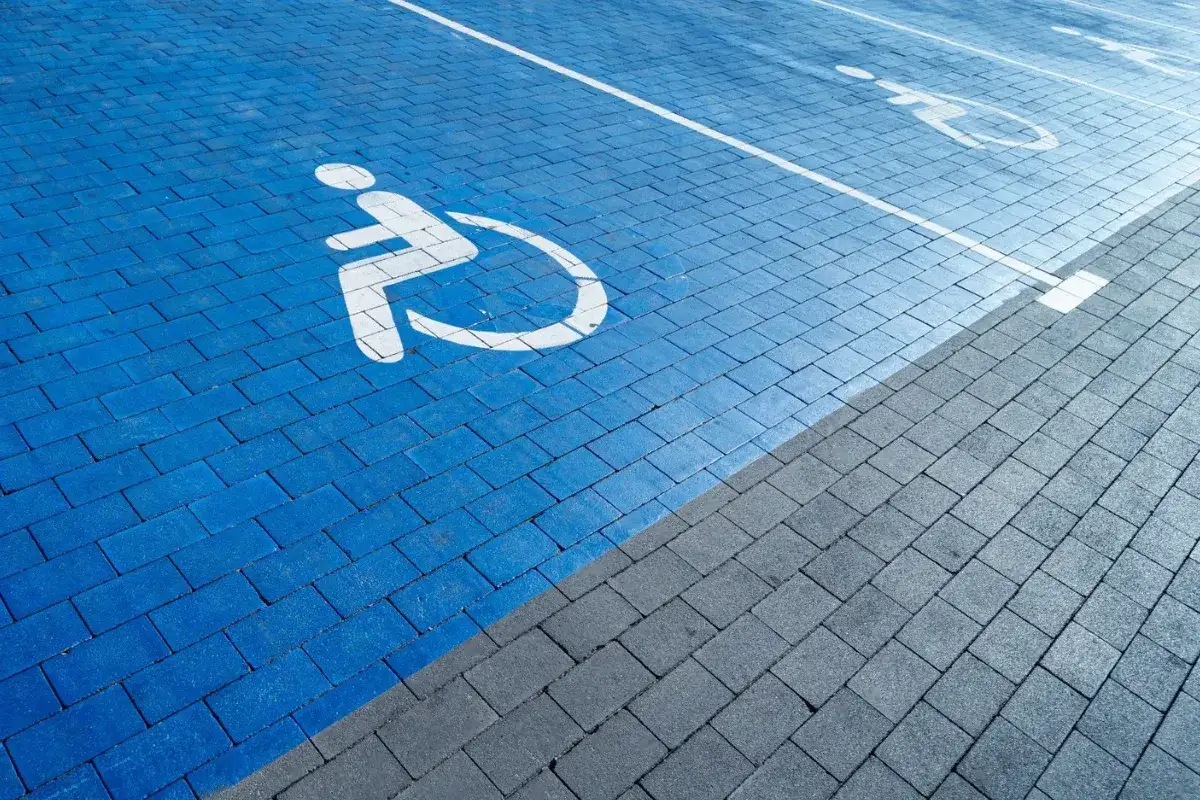 Niebieski parking z symbolem wózka inwalidzkiego. Orzeczenie o niepełnosprawności można uzyskać na wiele chorób, które ograniczają sprawność.