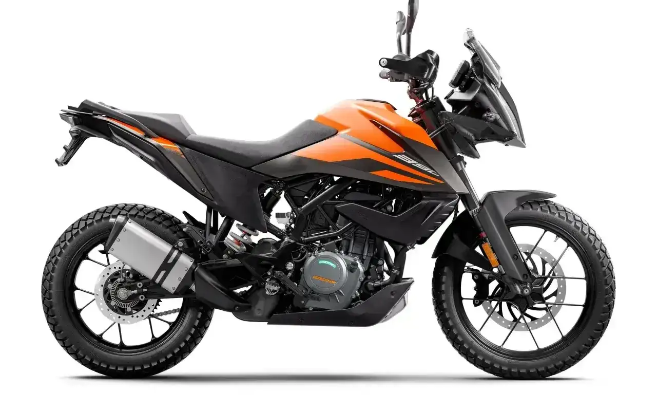 Pomarańczowy motocykl KTM 390 Adventure gotowy na przygodę, z agresywnym designem i terenowymi oponami.