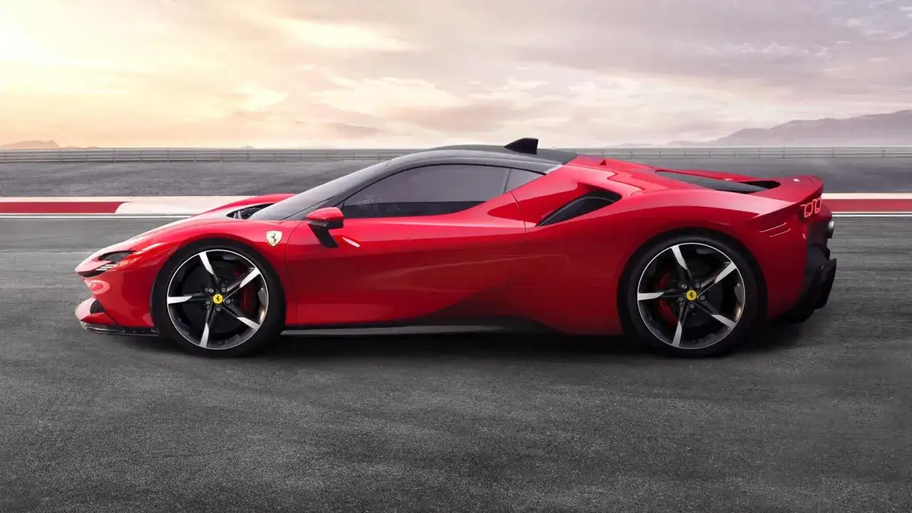 Czerwone Ferrari SF90 na torze wyścigowym, z czarnym dachem i felgami. Słońce zachodzi za górami.