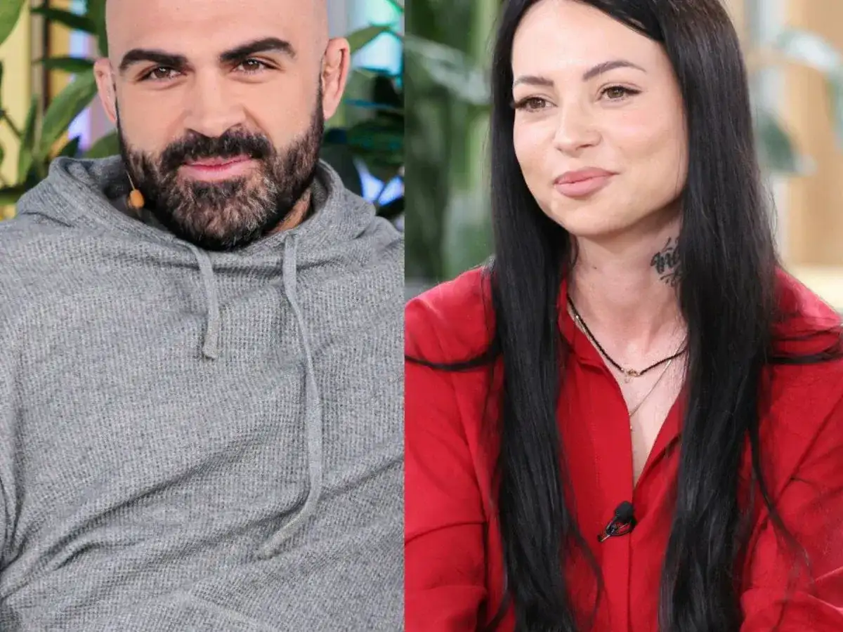 Akop i Sylwia Szostak, uśmiechnięci i patrzący w różne strony. On w szarej bluzie, ona w czerwonej koszuli.