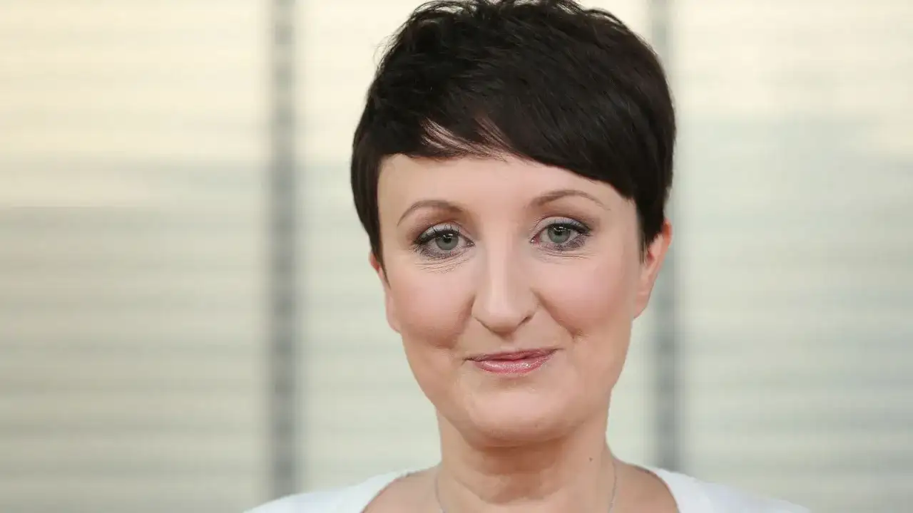Agnieszka Burzyńska zmagająca się z chorobą, patrzy w obiektyw z delikatnym uśmiechem.