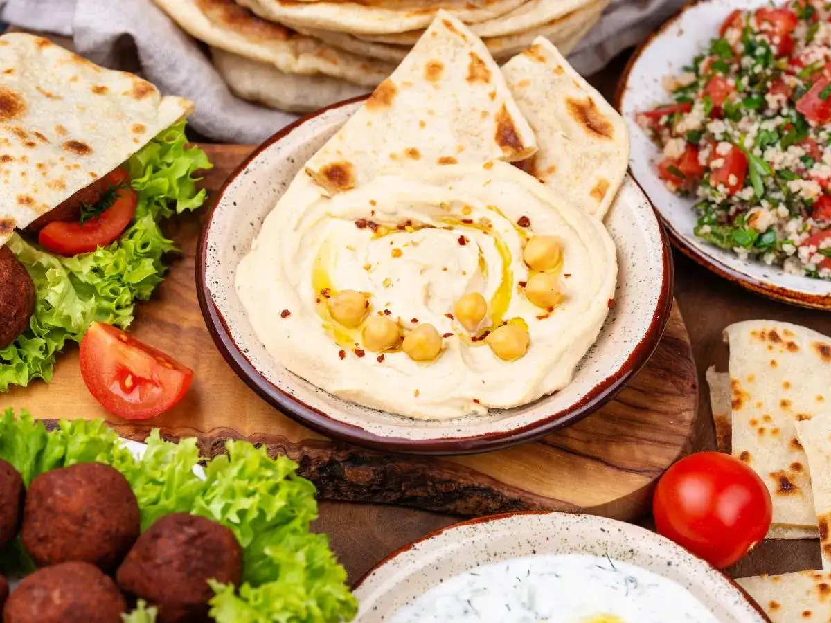 Pyszne dania kuchni libańskiej: kremowe hummus, falafel, sałatka tabbouleh i świeże pity. Idealne na wspólny posiłek.