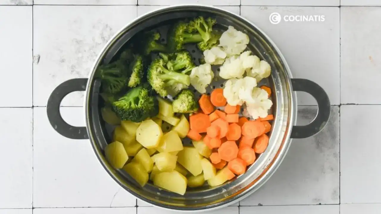 Un vaporizador lleno de un colorido panache de verduras: brócoli, coliflor, zanahorias y patatas cortadas.