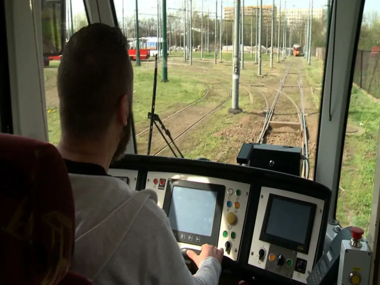 Mężczyzna za sterami tramwaju, być może uczestnik darmowego kursu na maszynistę, obserwuje tory.