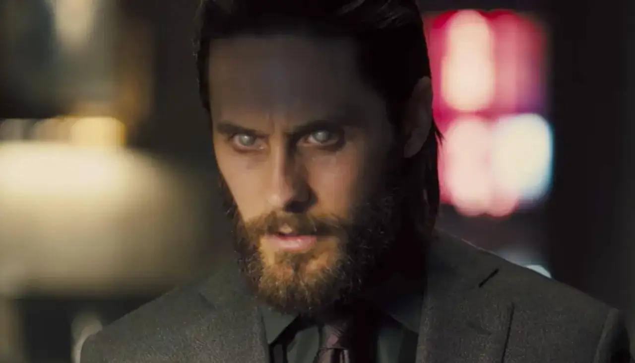 Jared Leto w filmach, z bladymi oczami i brodą, w garniturze.