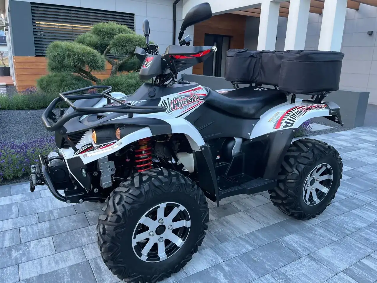 Hyosung TE 450 gotowy na przygodę. Biało-czarny quad z czerwonymi akcentami i bagażnikiem z tyłu.