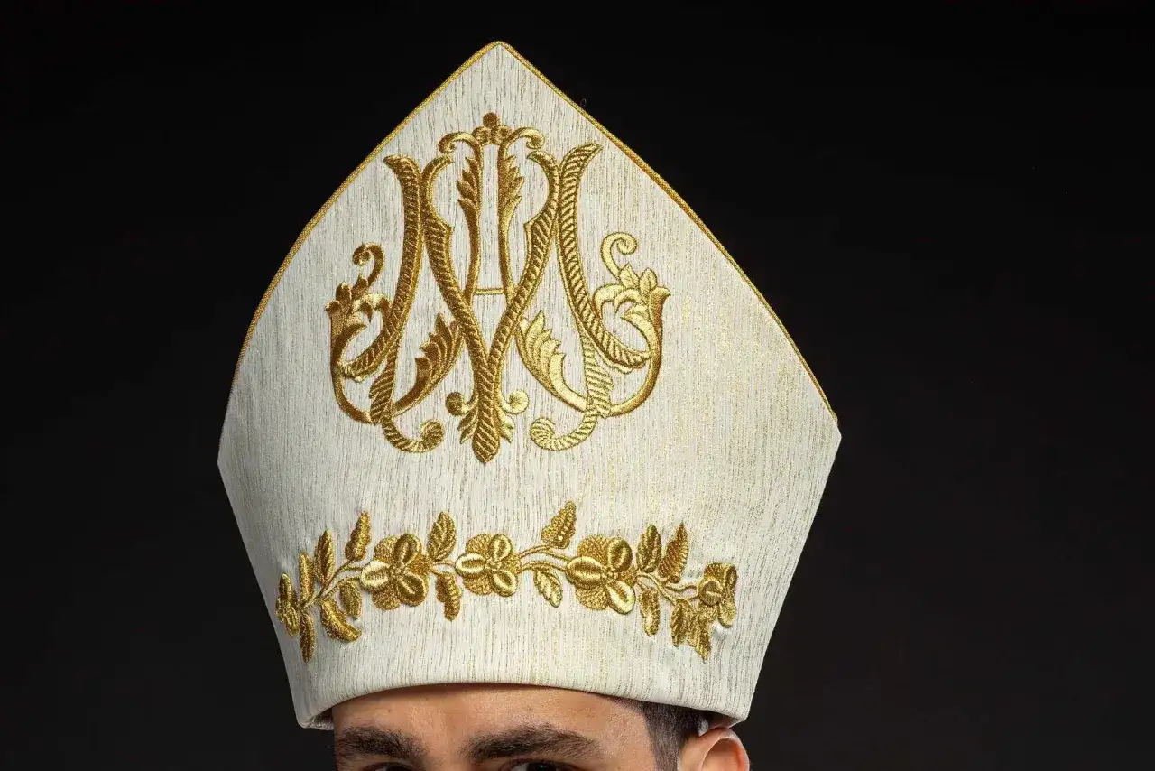 Biała mitra z haftem w kolorze złota, symbolizująca godność. Warto wiedzieć, jak się zwracać do biskupa, by okazać mu szacunek.