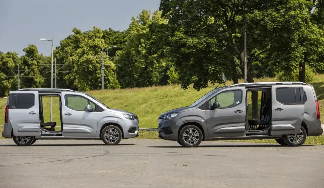 Dwa samochody Toyota Proace City Long w kolorach srebrnym i grafitowym stoją obok siebie z otwartymi drzwiami, ukazując wnętrze.