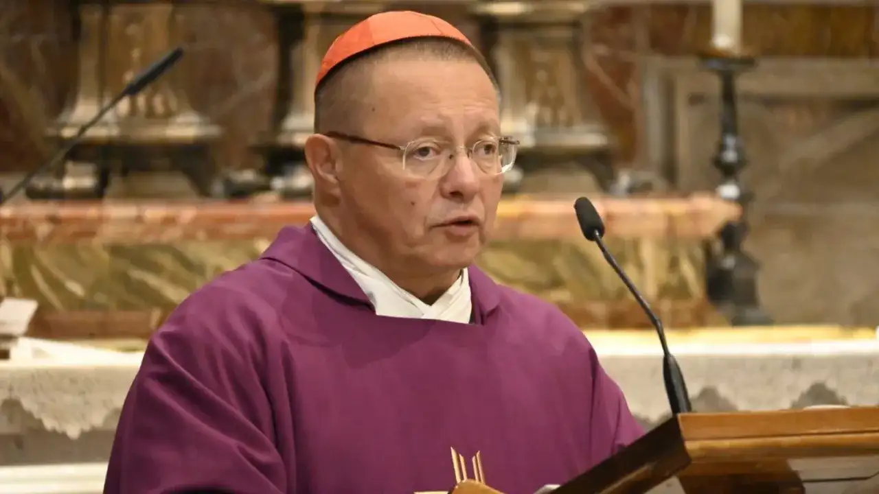 Biskup Ryś, w purpurowej szacie i z czerwoną piuską, przemawia przy mikrofonie, dzieląc się swoimi poglądami.