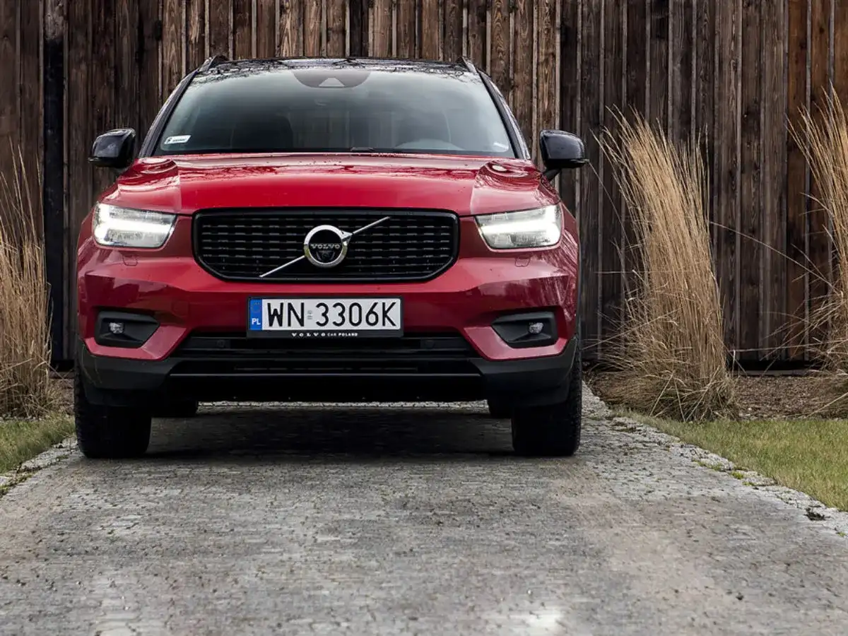 Czerwone Volvo XC40 na podjeździe. Zbliżenie na przód auta, gdzie widoczne są światła, grill i tablica rejestracyjna. Poznaj volvo xc40 wymiary.