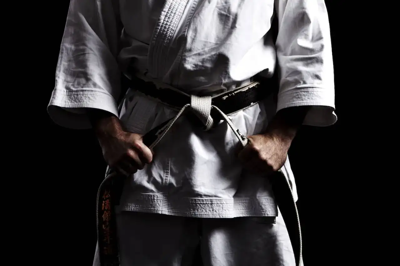 Mistrz karate w białym gi, z czarnym pasem, symbolizującym stopień mistrzowski.