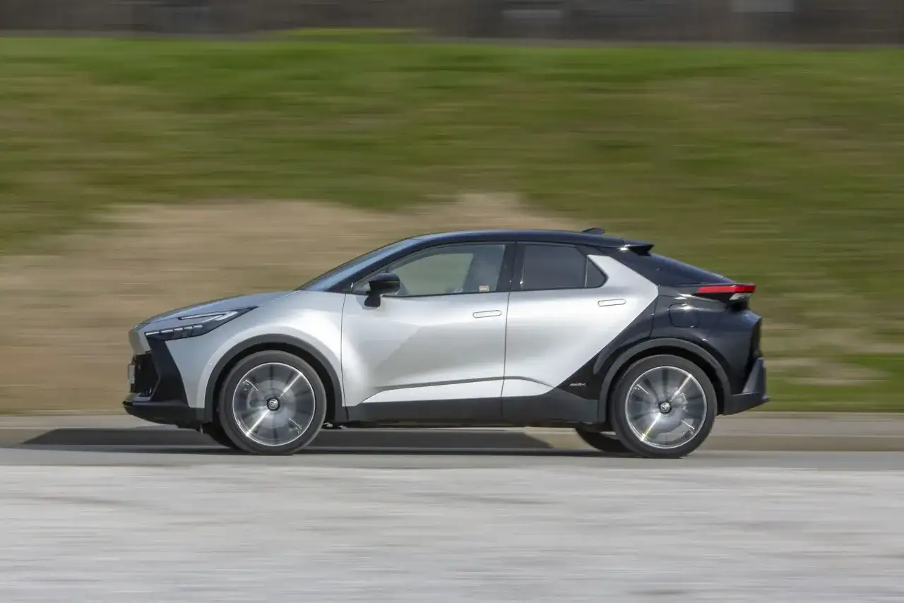 Srebrno-czarny Toyota C-HR 2019 w ruchu, z rozmytym tłem zieleni i drogi.