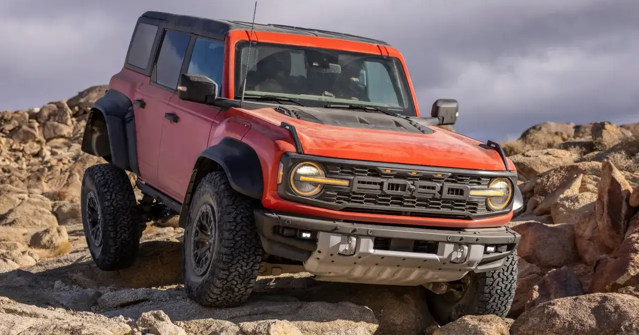 Pomarańczowy Ford Bronco Raptor pokonuje skalisty teren, demonstrując swoją terenową moc.