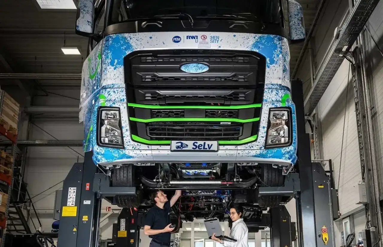 Deux techniciens travaillent sur un camion diesel futuriste, explorant son autonomie et ses innovations.