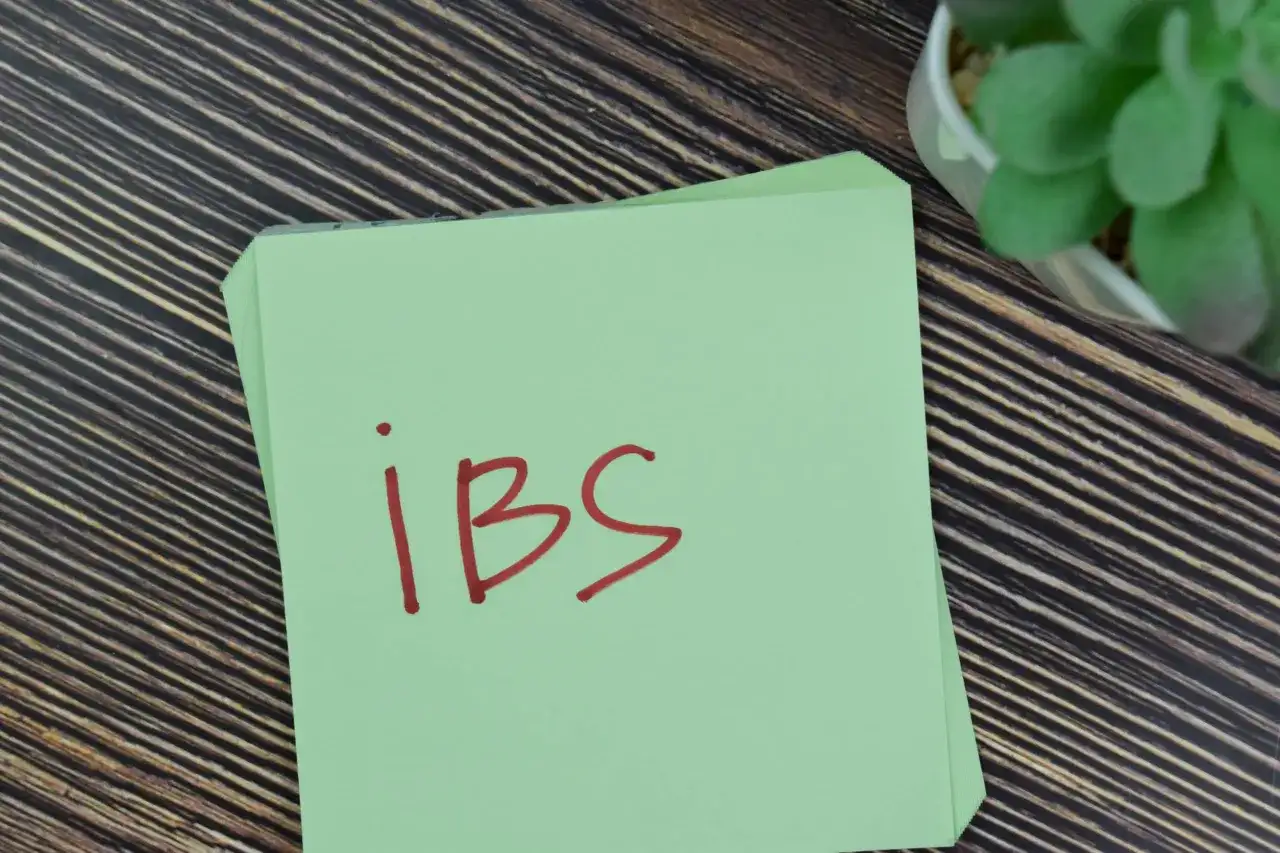 Zielona kartka z napisem "ibs" na drewnianym tle. Może to być przypomnienie o potrzebie leczenia, np. lekiem Duspatalin.