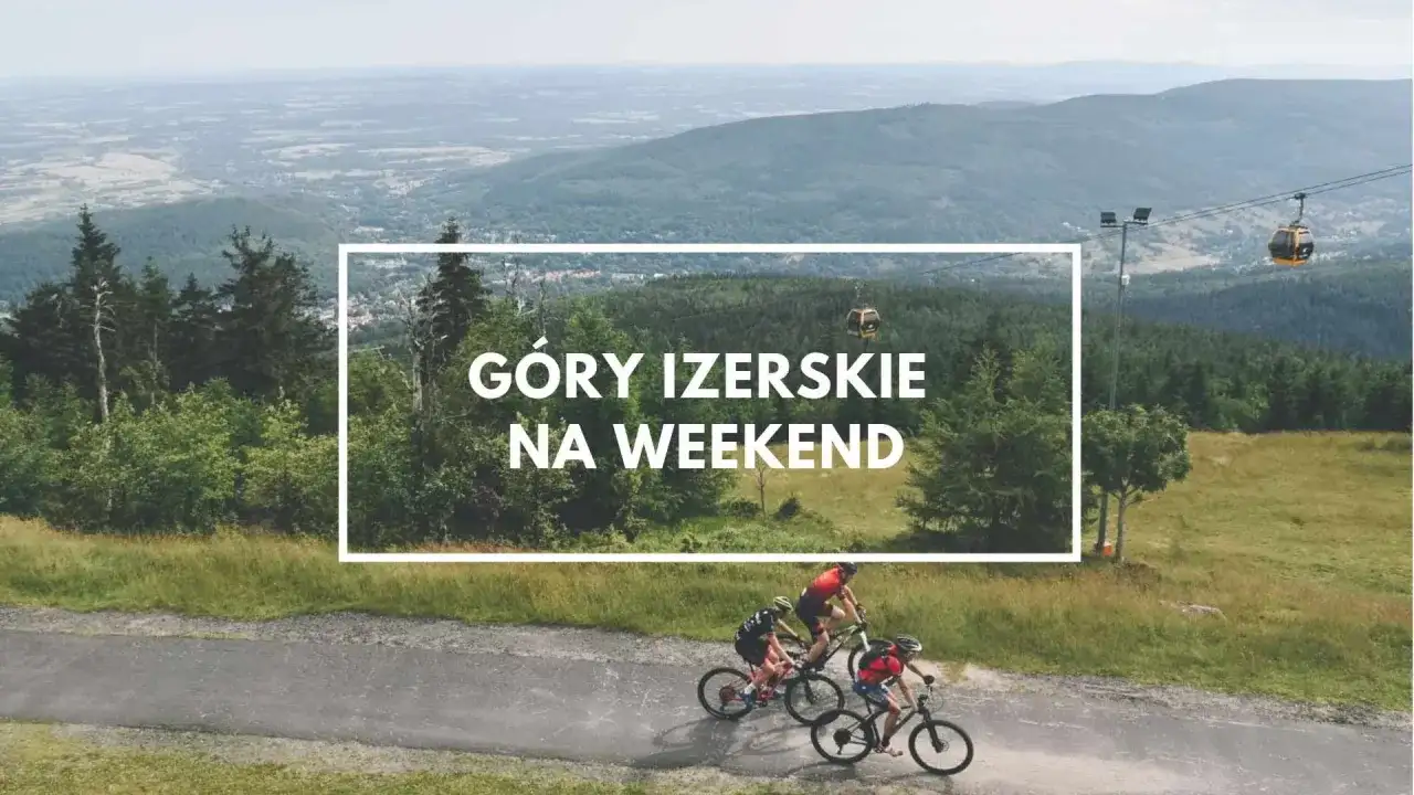 Góry Izerskie Polska: rowerzyści pędzą po górskiej drodze, w tle kolejka gondolowa i rozległy krajobraz.