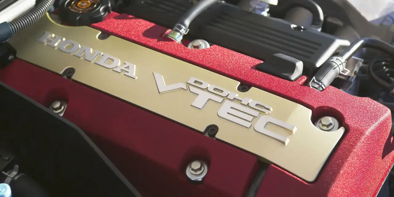 Złota pokrywa silnika Honda z napisem VTEC. Czerwone, teksturowane wykończenie dodaje sportowego charakteru.