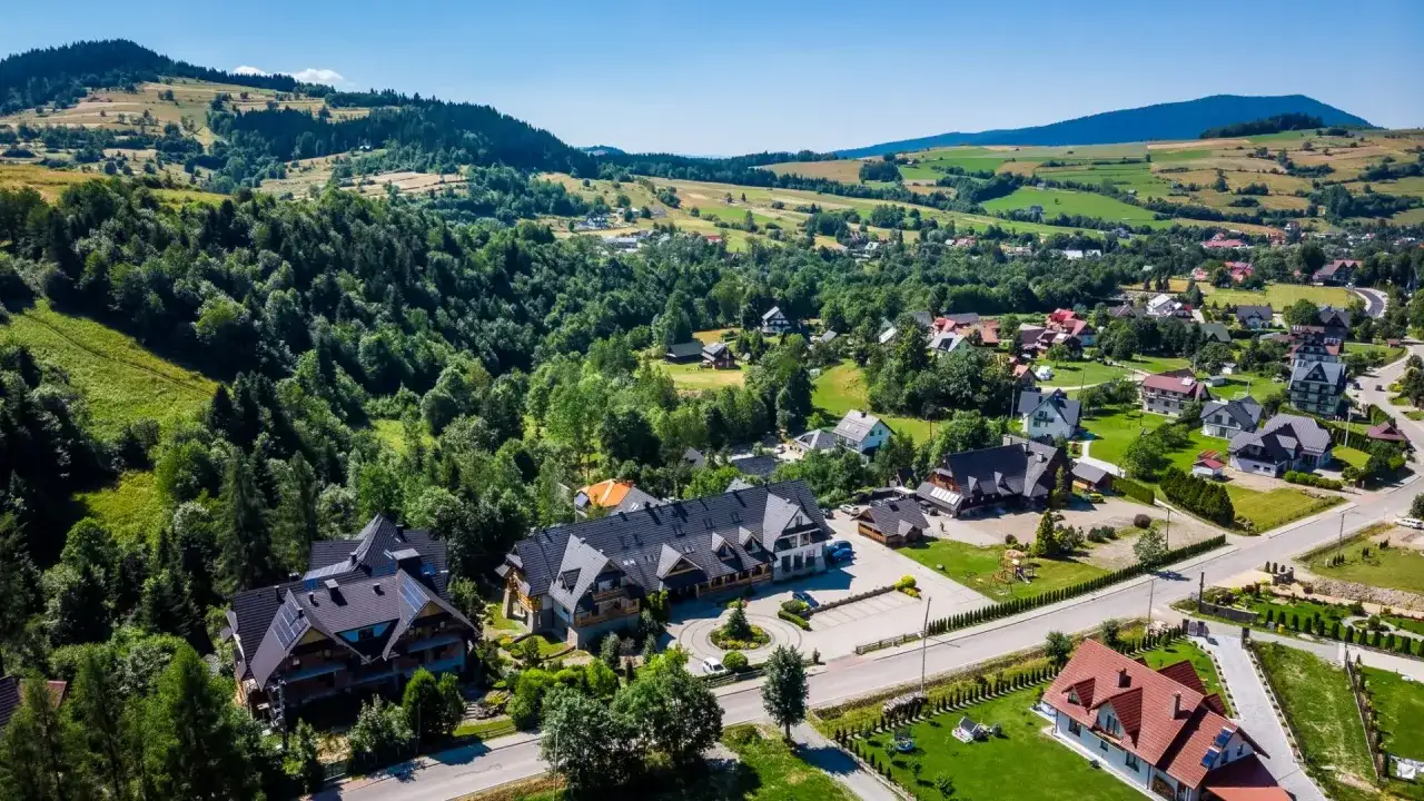Gorce: malownicza wieś z pensjonatami i domami w górskim krajobrazie. Idealne miejsce, by sprawdzić, gorce gdzie najlepiej nocować.