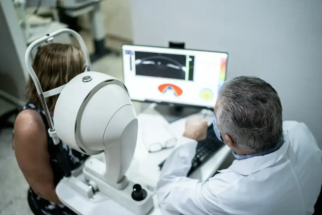 Lekarz bada pacjentkę za pomocą urządzenia do angiografii oka. Dowiedz się, jak się przygotować do badania.