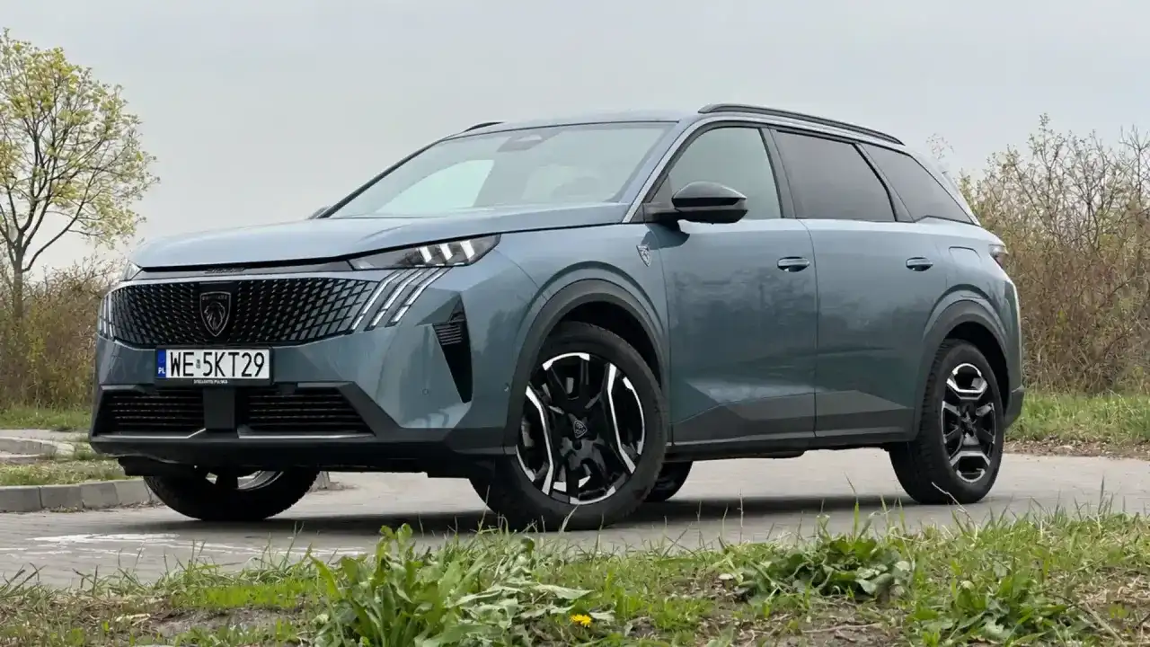 Nowy Peugeot 5008 w kolorze szarym, z czarnymi felgami i nowoczesnym grillem. Wiele osób szuka peugeot 5008 opinie przed zakupem.