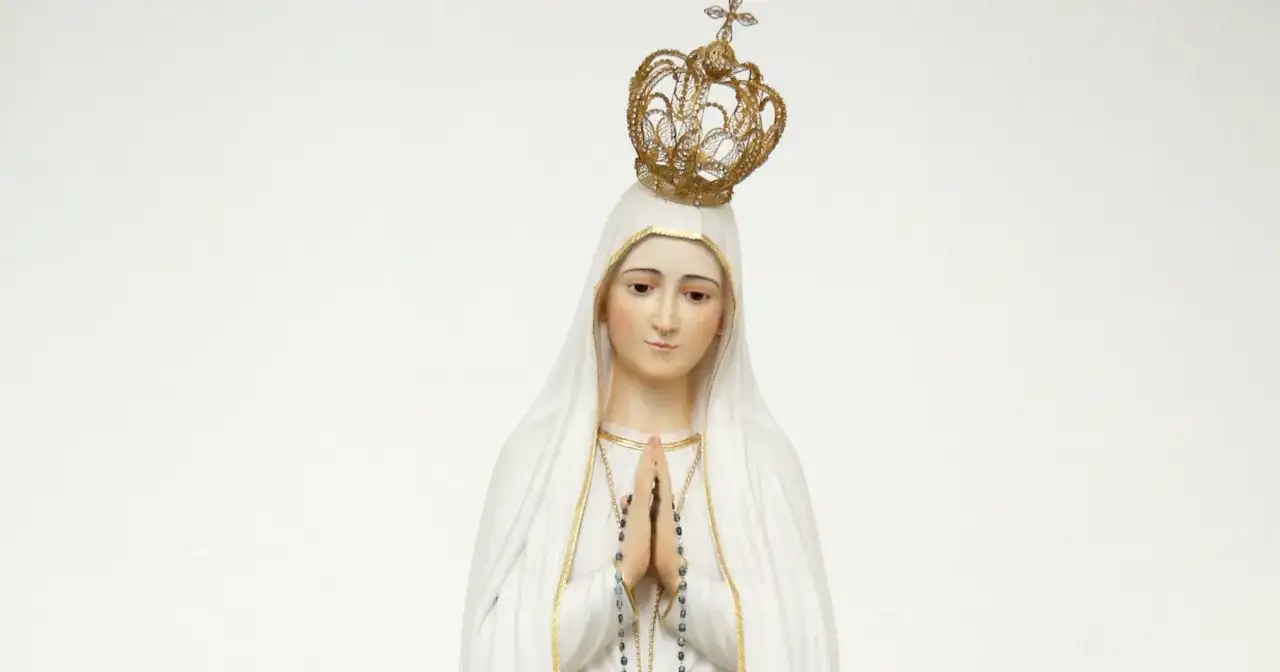 Figurka Matki Bożej Fatimskiej w białym welonie i złotej koronie, z rękami złożonymi do modlitwy.