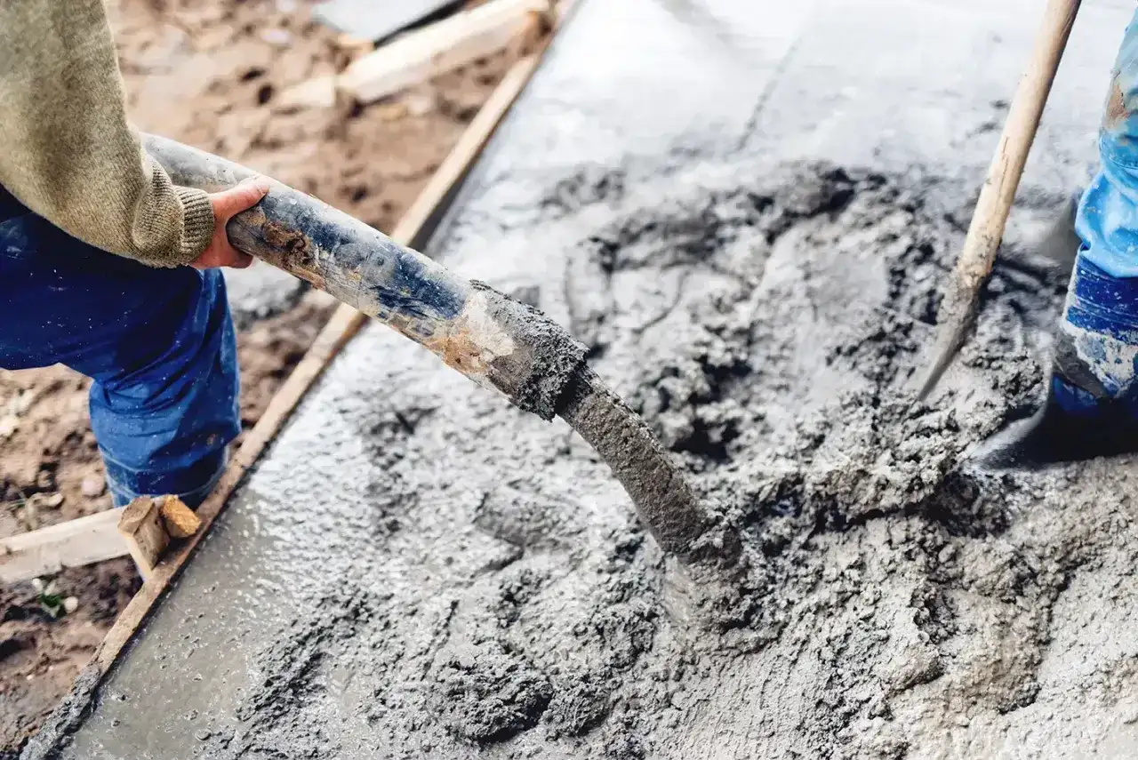 Pracownicy wylewają świeży beton. Właściwe suchy beton proporcje są kluczowe dla trwałości konstrukcji.