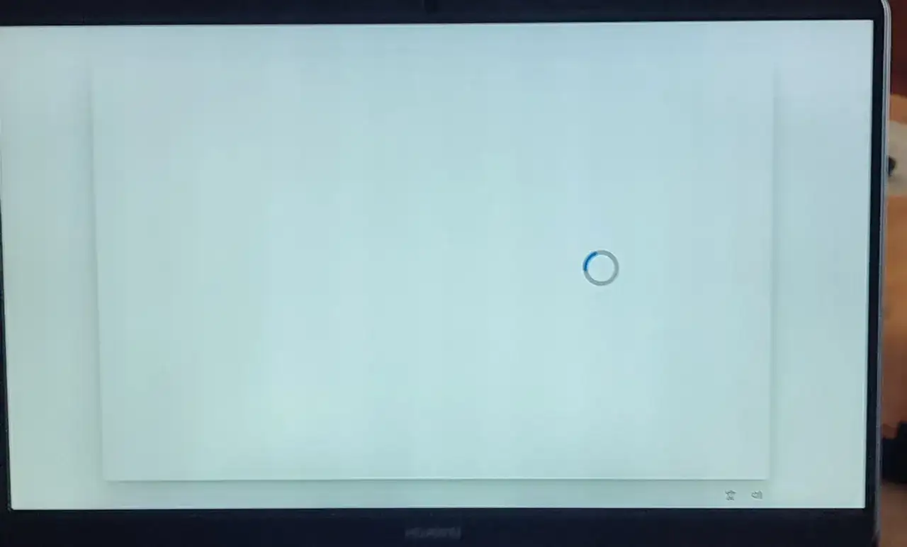 Jasny, biały ekran laptopa z niebieskim kółkiem ładowania pośrodku. Czekam na zakończenie procesu.